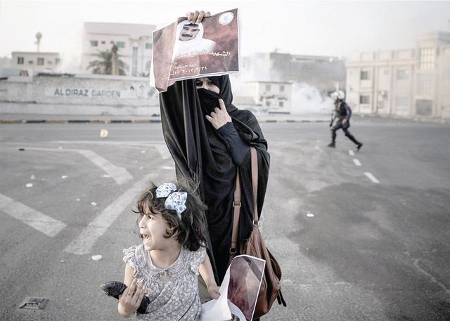 امرأة بحرينية برفقة ابنتها تحمل صورة المتوفى أثناء المواجهات - AFP