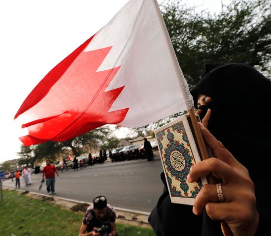 بحرينية تحمل القرآن وعلم البحرين خلال تظاهرة المعارضة أمس - reuters