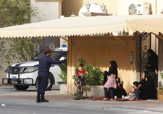 شرطي يتحدث إلى إحدى العوائل المعتصمة أمام منزلها  - REUTERS