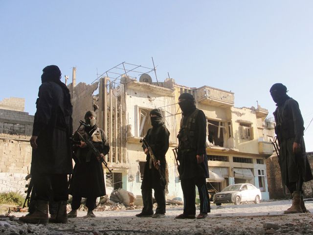 مقاتلو «جبهة النصرة» يقفون أمام أحد المباني المدمرة في حمص