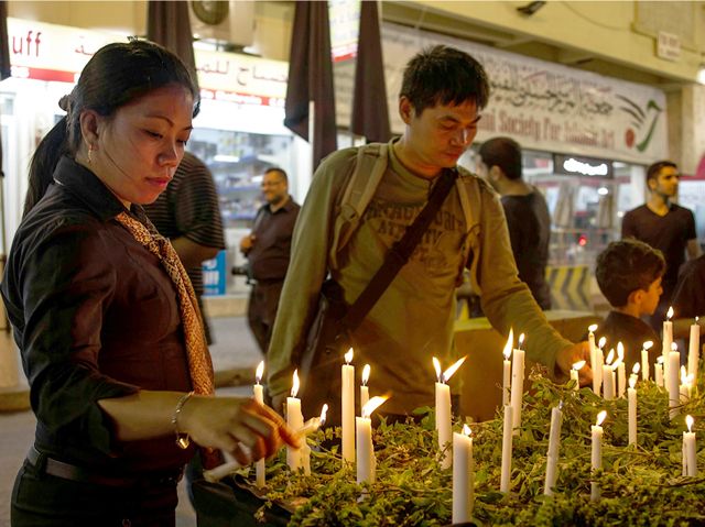 عدد من أفراد الجالية الفلبينية يشعلون الشموع في المنامة أمس