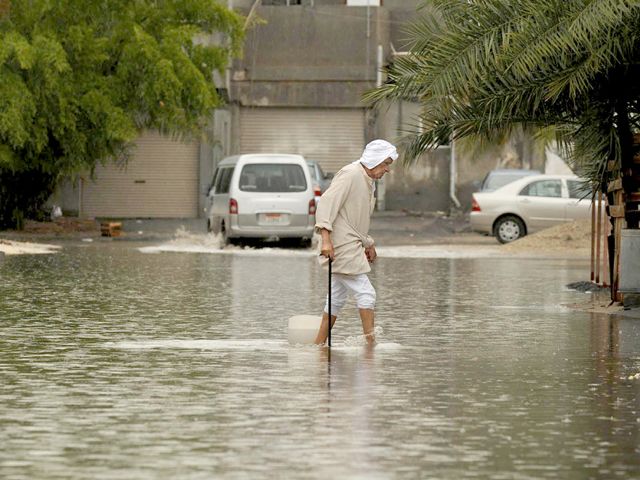 مواطن يعبر الطريق وسط مياه الأمطار  - تصوير : عيسى إبراهيم