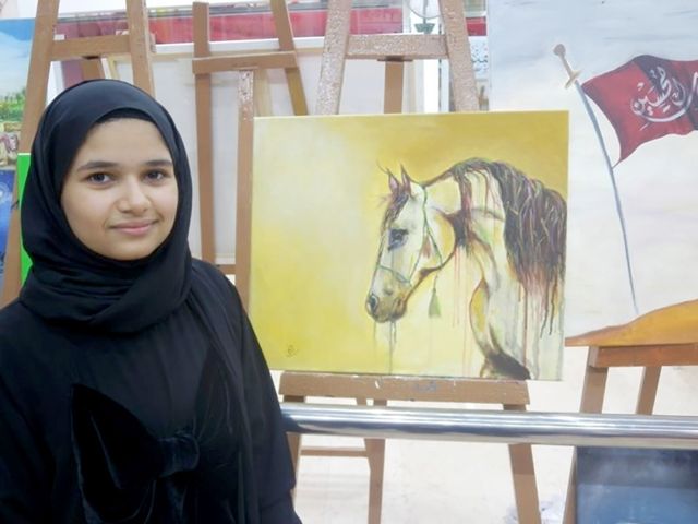 الطفلة إنجي العماني أمام لوحتها التي شاركته بها هذا العام