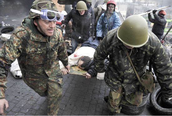 متظاهرون ينقلون أحد المصابين أثناء مواجهات أمس في كييف  - afp