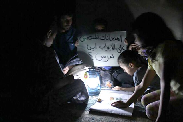 أطفال العائلة يدرسون في الظلام