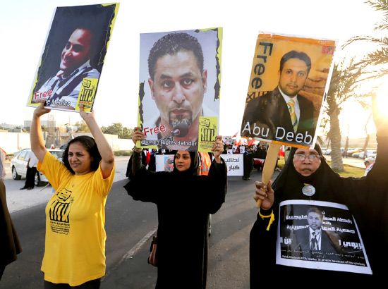 ... والمتظاهرون يرفعون صوراً للمعتقلين مطالبين بالإفراج عنهم-reuters