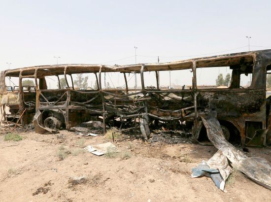 رجل عراقي يمشي بالقرب من الحافلة التي قتل فيها 52 سجيناً وتسعة من رجال الشرطة-REUTERS