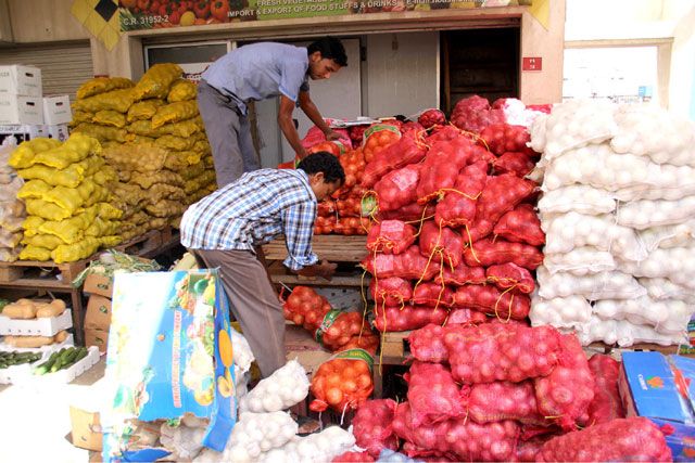 عمال يجهِّزون عدداً من المواد الغذائية في سوق المنامة المركزي