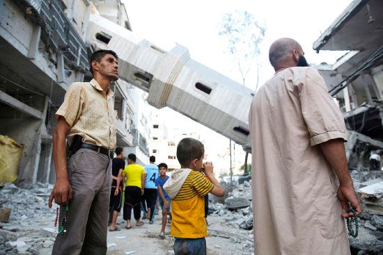 فلسطينيون يقفون بالقرب من مئذنة مسجد استهدفها القصف الإسرائيلي -reuters