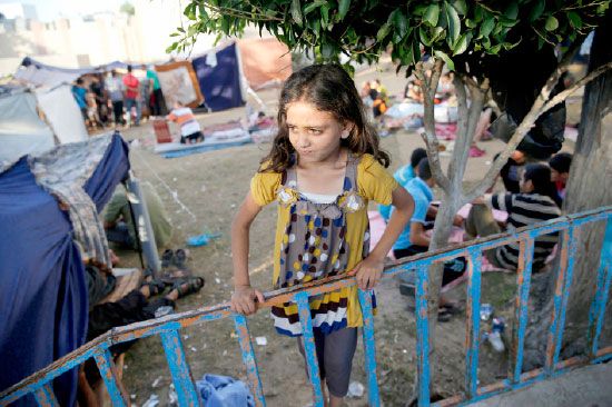 طفلة فلسطينية فرّت مع عائلتها من القصف تقف قرب مخيم أنشئ بمحاذات مستشفى «الشفاء» بقطاع غزة - reuters