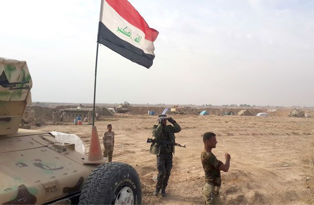عسكريون يرفعون علم العراق في موقع استراتيجي بمحافظة ديالى - AFP