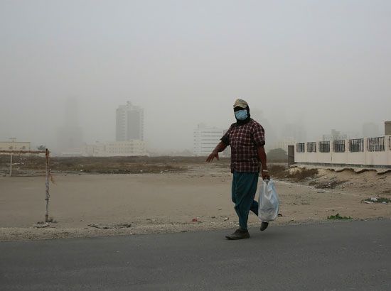 آسيوي يلثِّم نفسه احترازاً عن الغبار الذي شهدته البحرين أمس