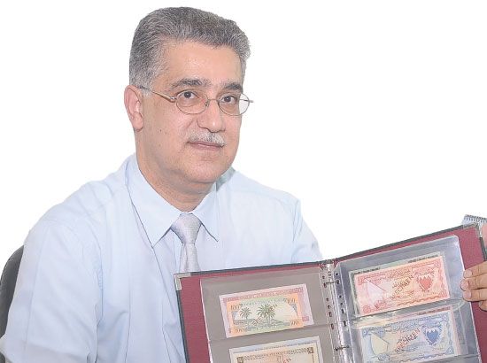 حافظ عبدالغفار حاملاً مجموعة من مقتنيات العملات الورقية لأول إصدار نقدي بحريني