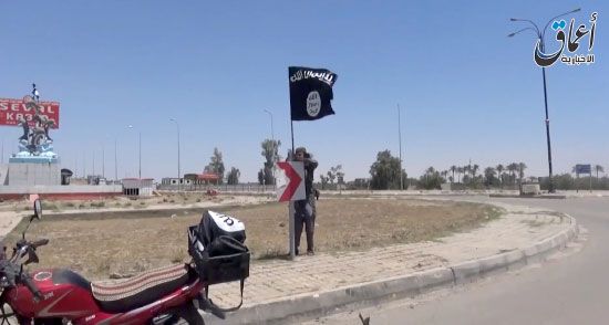 أحد عناصر «داعش» يرفع علم التنظيم في أحد شوارع الرمادي - afp