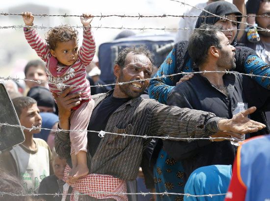طفل سوري لاجئ يمسك بالأسلاك على الحدود التركية - reuters