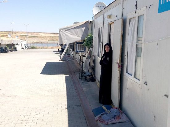 سيدة تقف أمام المساحة المخصصة لها وعينها ترقب العودة إلى سورية