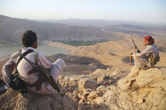 مسلحان من لجان المقاومة الشعبية والقوات الموالية للرئيس هادي، يجلسان على جبل يطل على سد مأرب - afp