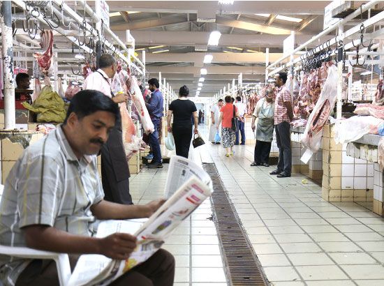جزار يقرأ الصحيفة بعد توقفه عن العمل لغياب المستهلكين أمس - تصوير عقيل الفردان