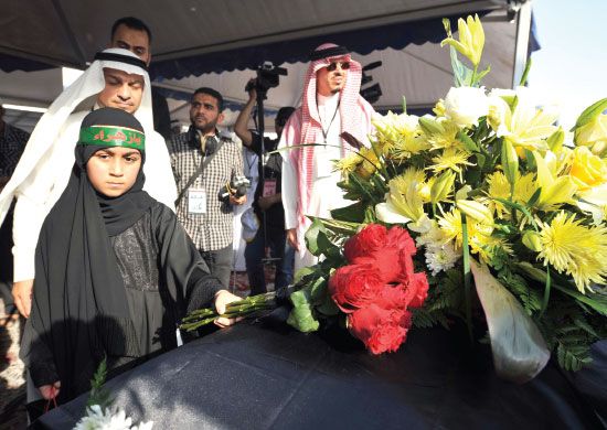 فتاة تضع الزهور على نعش أحد الضحايا خلال جنازة في مدينة القطيف