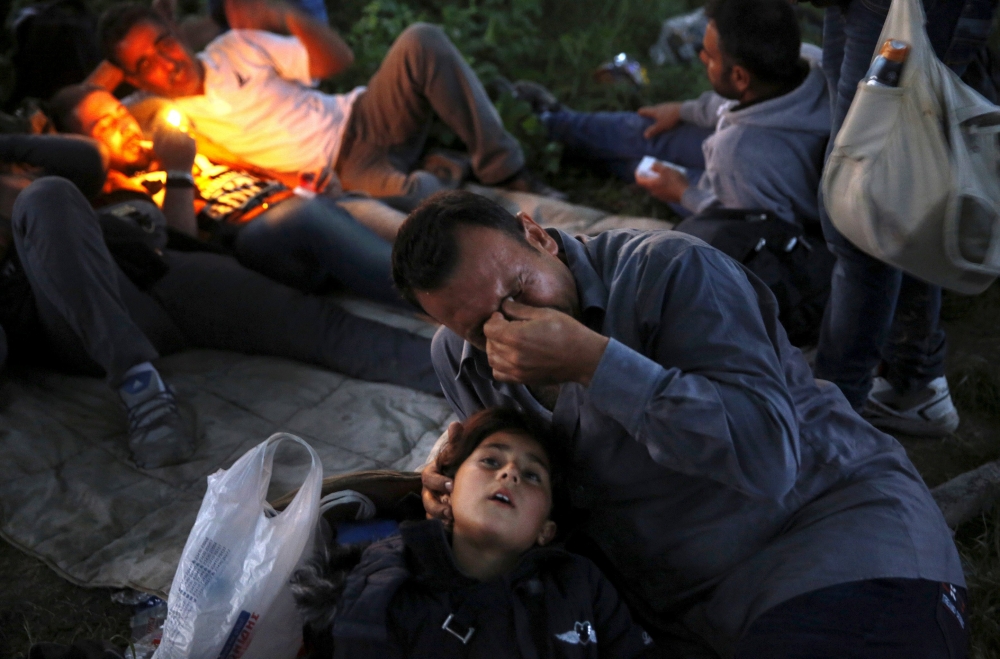 مهاجر سوري يبكي بجوار ابنه على الحدود اليونانية (14 مايو 2015)