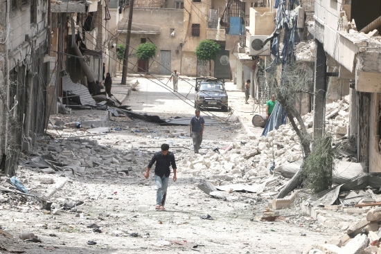 ﻿سوريون يمشون وسط أنقاض مبانٍ مدمرة في حلب أمس - reuters