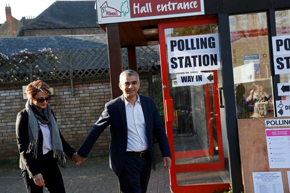 صادق خان مع زوجته بعد الإدلاء بصوتهما خارج مقر الاقتراع جنوب لندن أمس (الخميس)