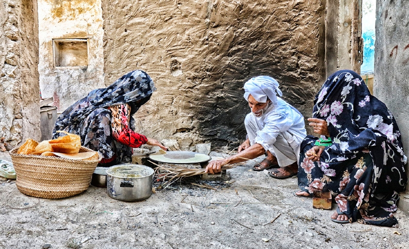 ﻿إعداد خبز التاوه بالطريقة القديمة يتطلب إشعال النار في سعف النخيل - تصوير محمد المخرق
