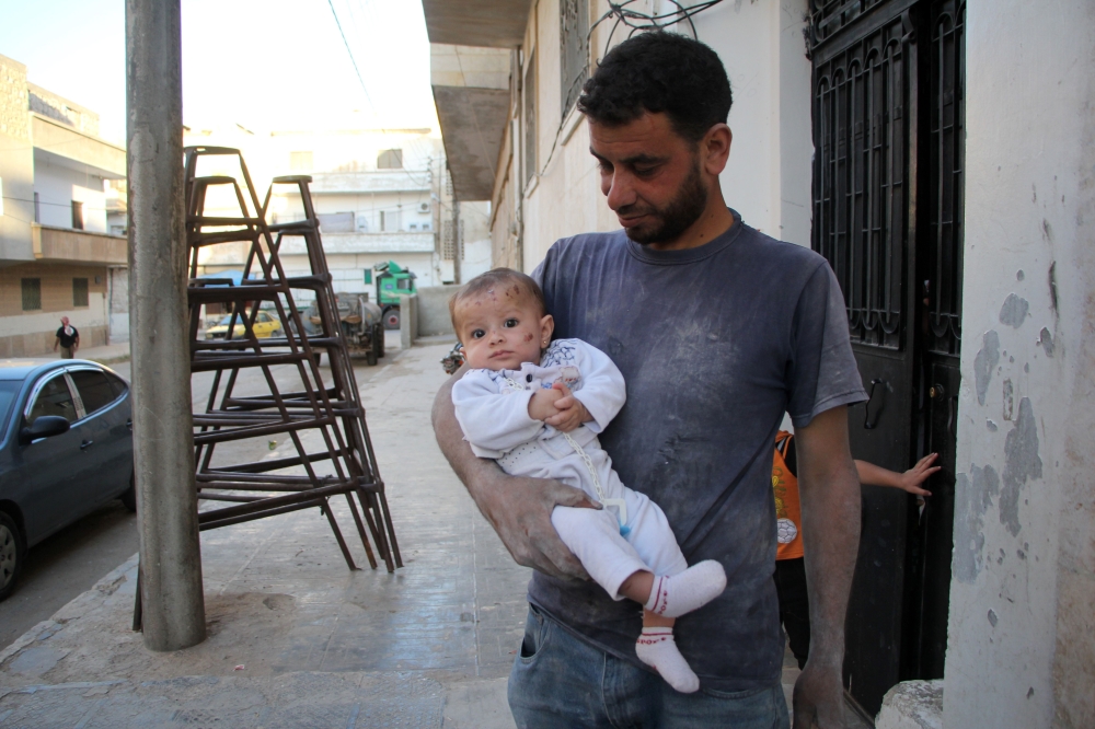 يحيى معتوق يحمل ابنته وحيدة (4 أشهر) أمس السبت إذ تم انقاذها في إدلب. أ ف ب