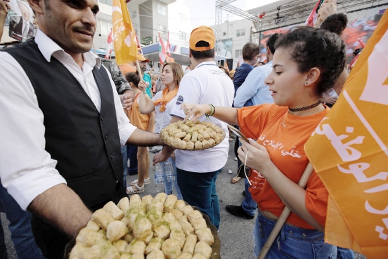 ﻿رجل لبناني يقدم الحلوى في أحد شوارع بيروت احتفالاً بانتخاب ميشال عون رئيساً للبلاد - afp