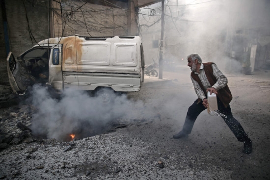﻿رجل سوري يحاول إطفاء حريق نشب بسبب الغارات الجوية في بلدة يسيطر عليها المتمردون في دوما - afp