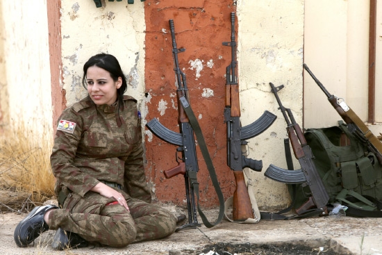 ﻿فتاة إيزيدية تقاتل مع قوات البيشمركة بجانب بنادق في بلدة بعشيقة