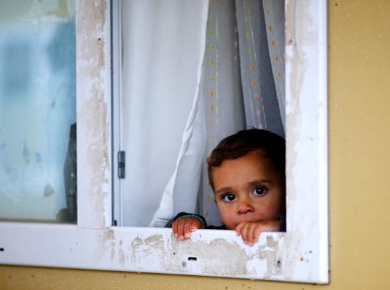 ﻿طفل سوري يطل من نافذة في مخيم للاجئين بالقرب من الحدود التركية السورية - reuters