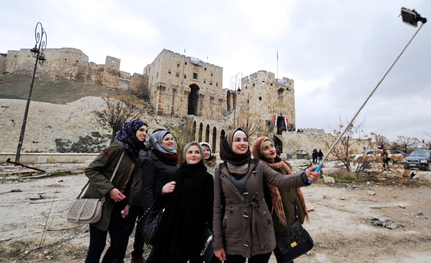 ﻿نساء يلتقطن صورة «سيلفي» خارج قلعة حلب التاريخية في منطقة تسيطر عليها الحكومة - REUTERS