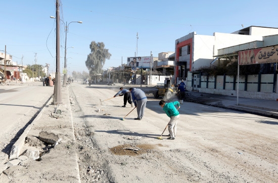 ﻿عراقيون ينظفون الشوارع بعد العودة إلى منازلهم في حي الزهور في الموصل - reuters