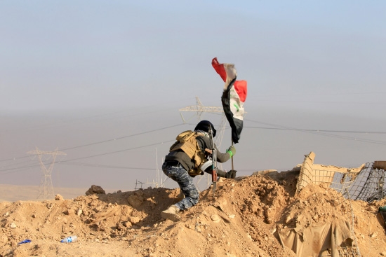 ﻿جندي عراقي يضع العلم العراقي خلال المعركة مع «داعش» جنوب الموصل - reuters
