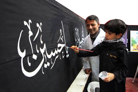 الخطاط محمد رضا يوجه  أحد الأطفال