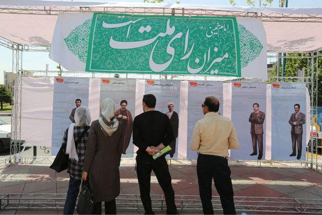 إيرانيون ينظرون إلى صور للرؤساء الإيرانيين السابقين - AFP