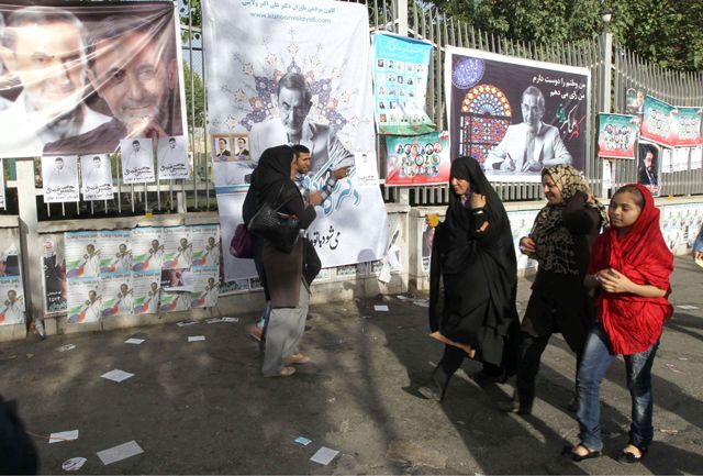   إيرانيون يسيرون بالقرب من لافتات دعائية لمرشحي الانتخابات الرئاسية الإيرانية في طهران - AFP