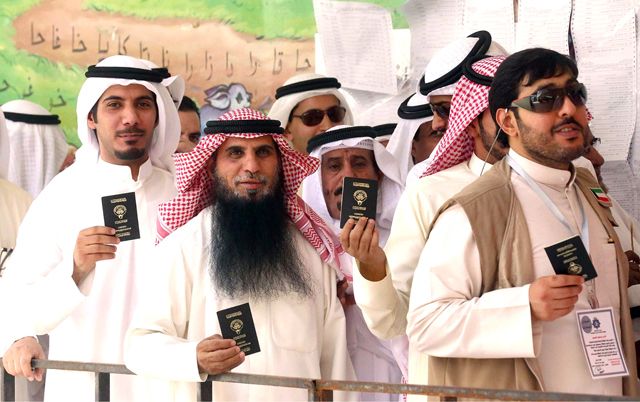 كويتيون يحملون بطاقاتهم (الهوية) في طريقهم لمركز التصويت - AFP