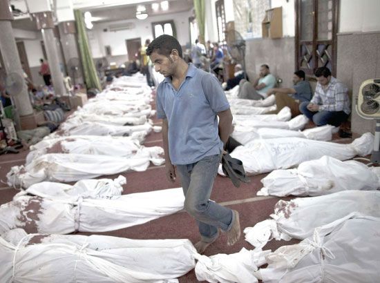 مصري يمر بين جثث ضحايا أحداث أمس في القاهرة - afp