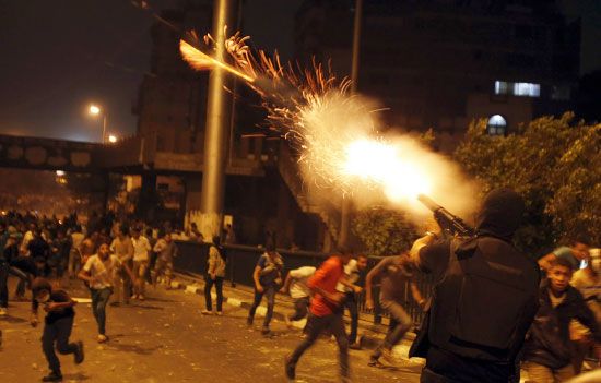 عنصر من قوات مكافحة الشغب يطلق قنبلة مسيلة للدموع أثناء مواجهات في القاهرة - reuters