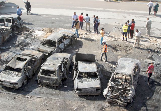 عراقيون يقفون في موقع هجوم بسيارة ملغومة في بغداد - REUTERS