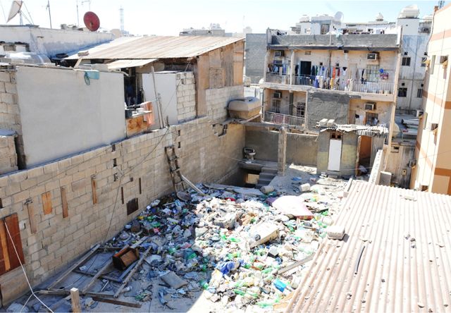أحد منازل العزاب الأسيويين في المنامة والقمامة على السطح