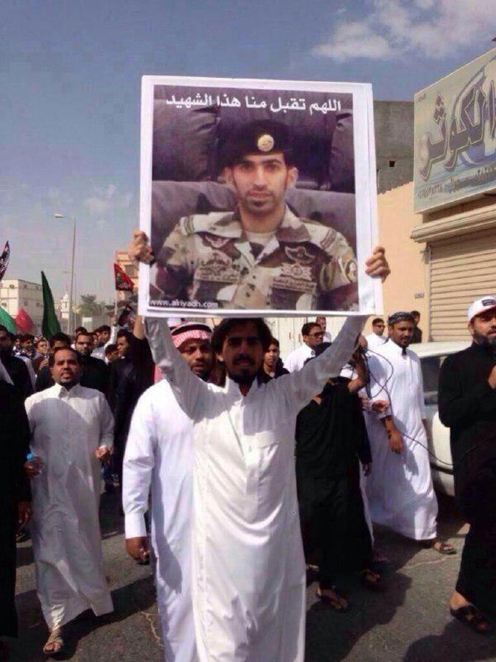 أهالي الإحساء خلال تشييع ضحاياهم يرفعون صور الجنود الذين قتلوا أثناء مواجهة الإرهابيين الذين نفذوا الهجوم على حسينية المصطفى