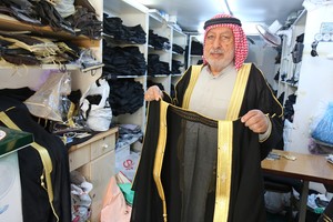 جواد التاجر يعمل في مهنة خياطة البشوت في المحرق