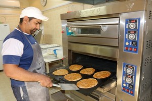 بحريني يزاول عمله في صناعة خبز الأحمر بالسمسم 